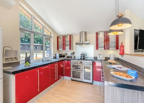 A modern kitchen with red cabinets, stainless steel appliances, and a large window.
