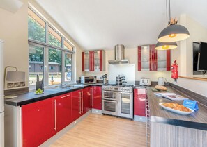 A modern kitchen with red cabinets, stainless steel appliances, and a large window.