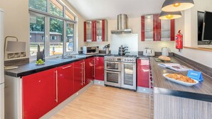 Una cocina moderna con armarios rojos, electrodomésticos de acero inoxidable y un ventanal amplio.