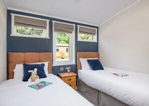 Une chambre avec deux lits, une fenêtre et une table de chevet avec une lampe.