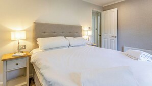 Une chambre d’hôtel avec un lit, des tables de chevet, une lampe, une porte et un radiateur.