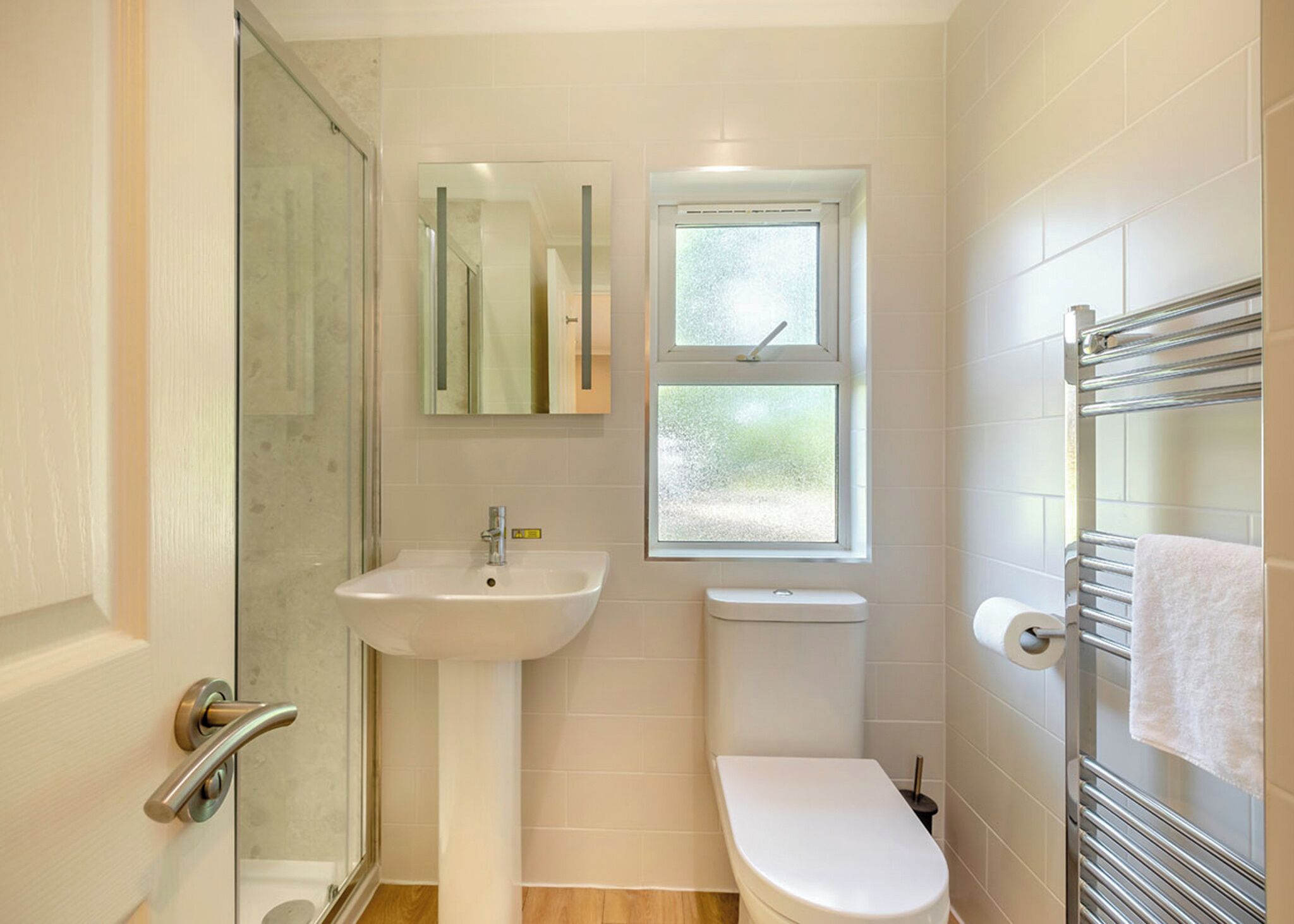 Un bagno con cabina doccia in vetro, lavandino, WC e porta asciugamani.
