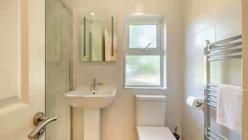 Un bagno con cabina doccia in vetro, lavandino, WC e porta asciugamani.