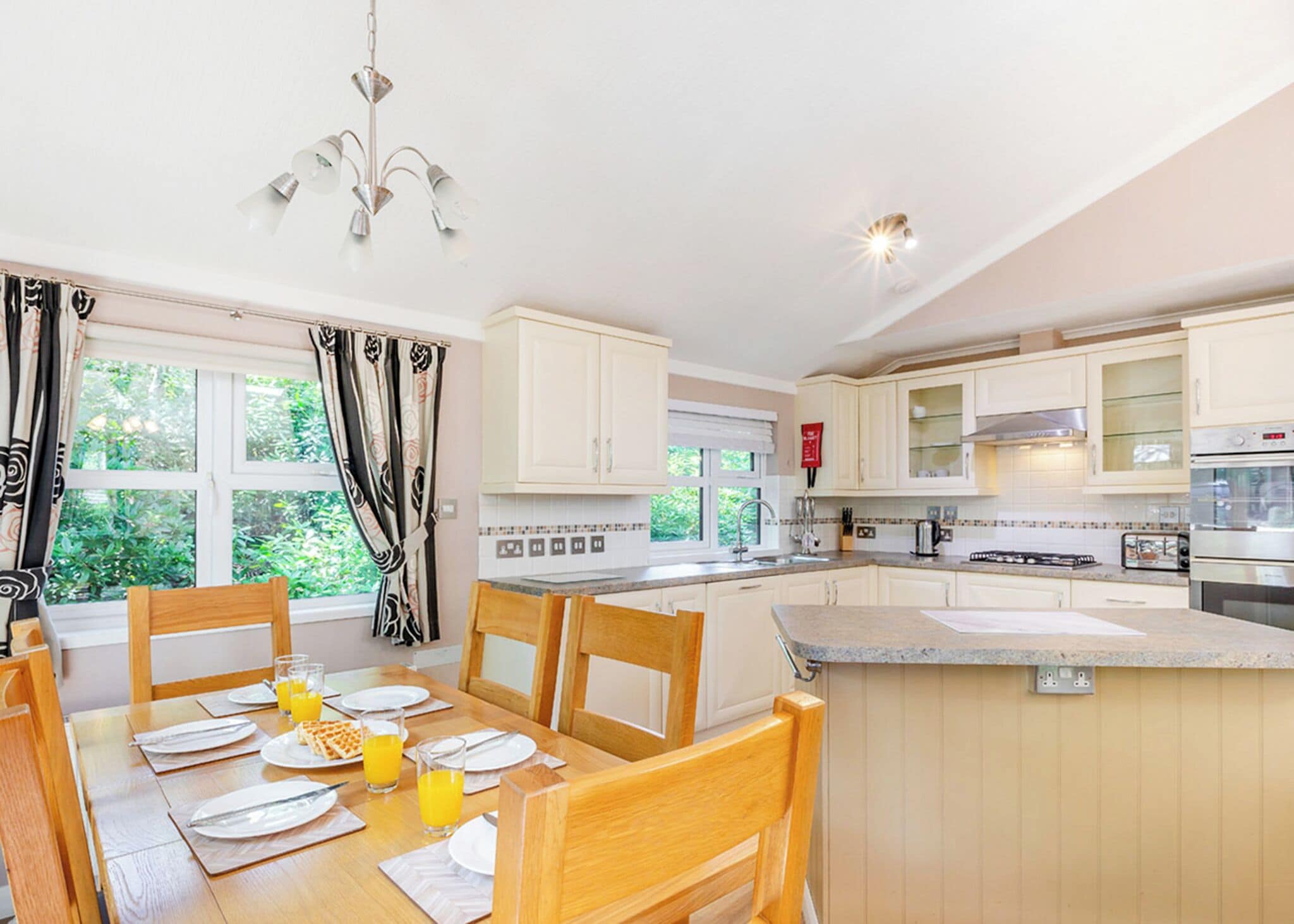 A modern kitchen with white cabinets, a dining table set for breakfast, and a large island.