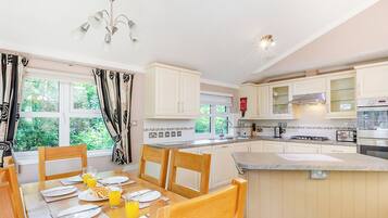 A modern kitchen with white cabinets, a dining table set for breakfast, and a large island.