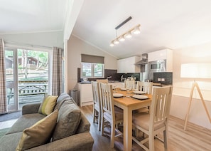 A modern kitchen with a dining area, a sofa, and a view of the outdoors. - Superior 3, Slps 6, parking, decking (Near Weymouth)