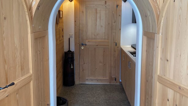 Un estrecho pasillo con paredes de madera y una puerta al final.