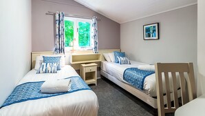 Ein Doppelzimmer mit zwei Betten, einem Schreibtisch, einem Stuhl und einem fensterbepflanzten Fenster.