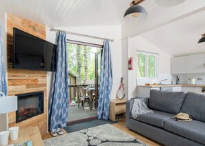 A cozy living room with a fireplace, a sofa, and a dining area with a view of the outdoors.