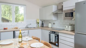 Eine moderne Küche mit weißen Schränken, einer Mikrowelle, einem Toaster und einem Essbereich mit Tisch für zwei Personen.