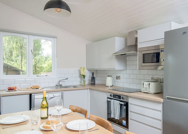 A modern kitchen with white cabinets, a microwave, a toaster, and a dining area with a table set for two.