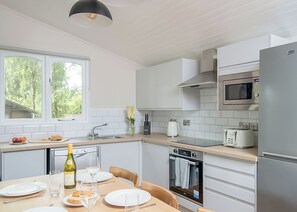 A modern kitchen with white cabinets, a microwave, a toaster, and a dining area with a table set for two.