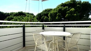 Un espace extérieur abrité, aménagé avec une table ronde et quatre chaises, le tout entouré d’une rambarde blanche.