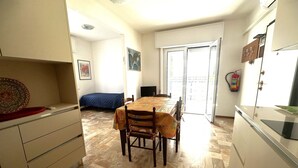 Une cuisine compacte avec un coin repas, un lit et une porte-fenêtre coulissante donnant sur un balcon extérieur.
