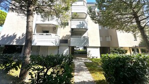 Un immeuble résidentiel à plusieurs étages, doté de balcons et entouré d’arbres et de verdure.