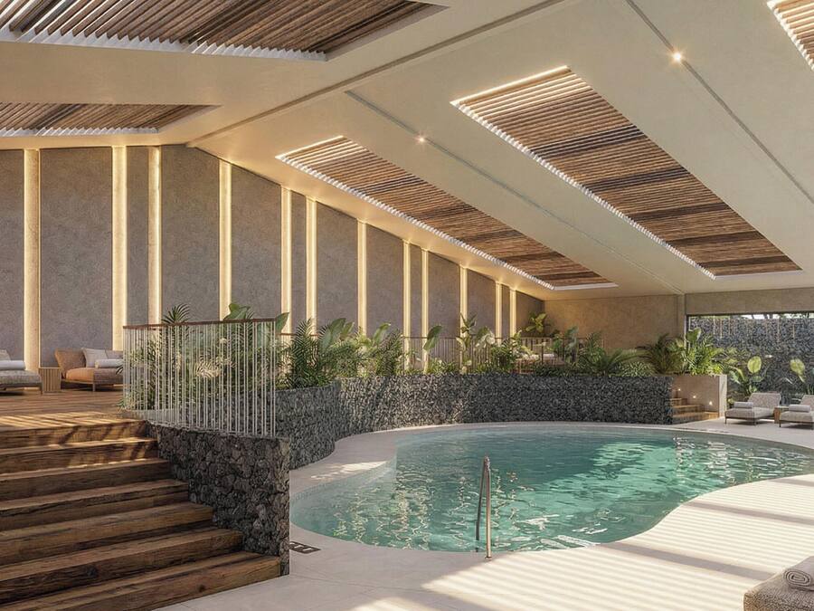 A modern indoor pool area with a stone wall, wooden steps, and lounge chairs.