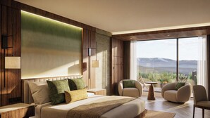 A modern hotel room with a large bed, two armchairs, a small table, and a view of mountains through large windows. - Montara Hotel, Tapestry Collection by Hilton (Ángeles)