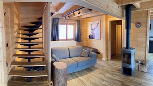 Ein Holzinnenraum mit einer Wendeltreppe, einem Sofa, einem Kamin und einem Bild von einem Hirsch.