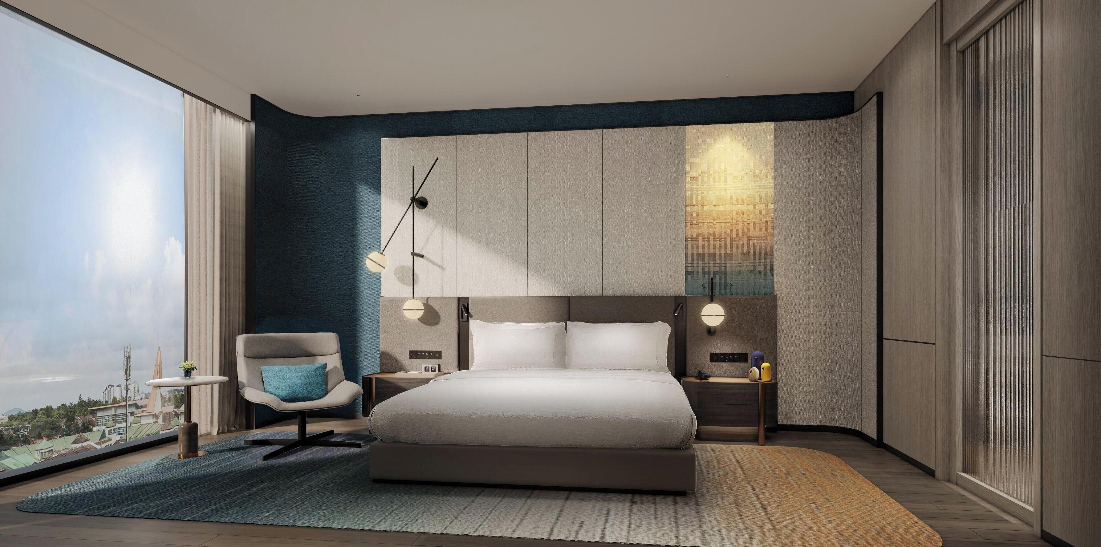 A modern bedroom with a large bed, bedside tables, a chair, and a view of the city.