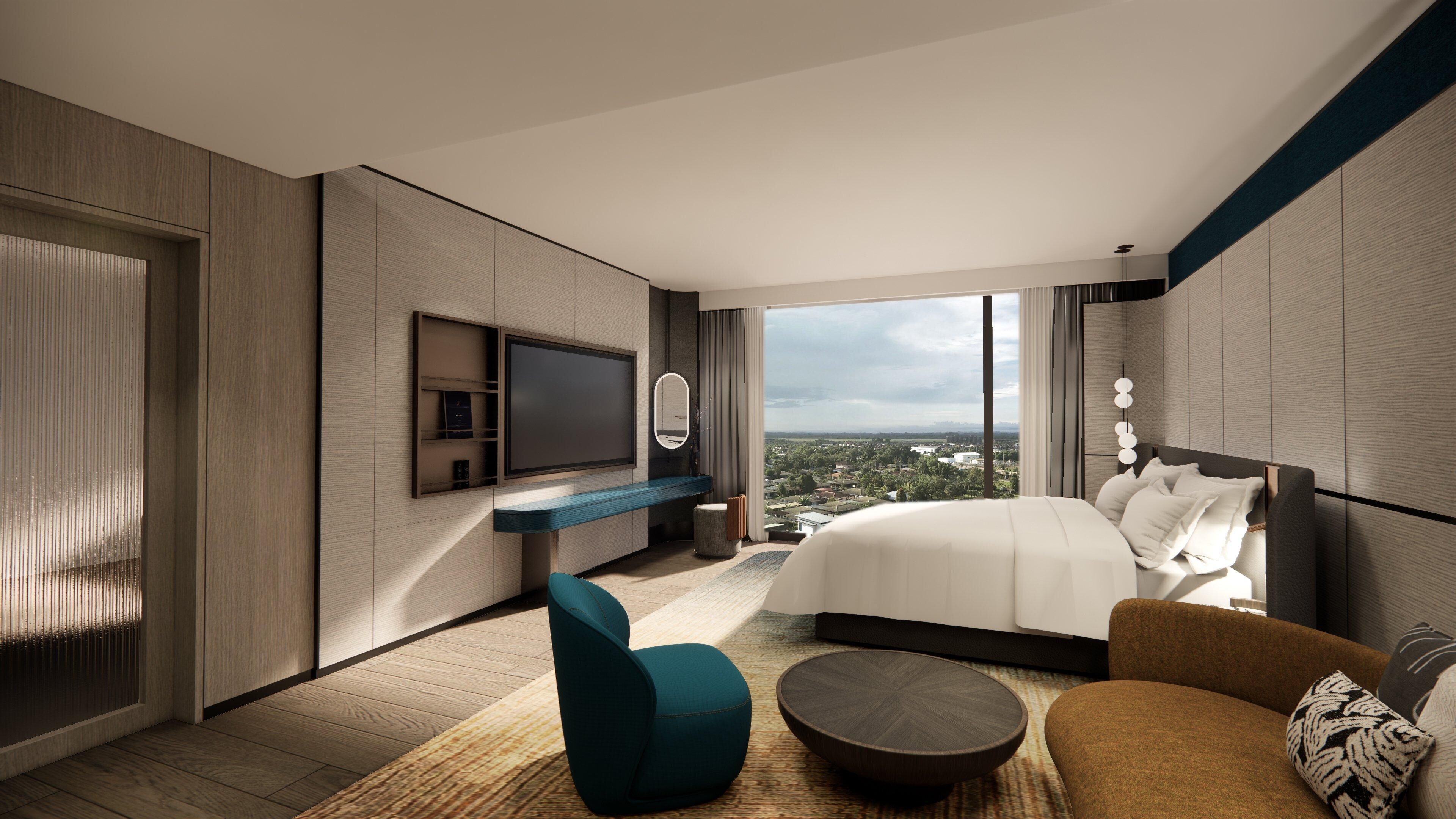 A modern hotel room with a large bed, a TV, a seating area, and a view of the city.
