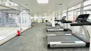 A gym with treadmills, a fire extinguisher, and large windows. - Bloomfields Pretty Stu in Oasis  (Abu Dhabi)