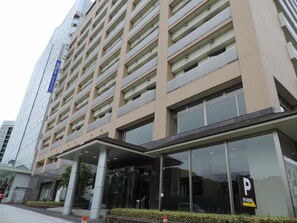 A multi-story hotel with a modern facade, a covered entrance, and a parking sign. - Dormy Inn Akita (Akita)