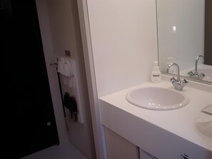 Un baño moderno con un lavamanos blanco, un espejo y un perchero para toallas.