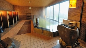 Una spa con una vasca da bagno ampia, una scultura in pietra e vista sull'esterno.