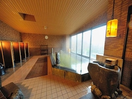 Un cuarto de spa con una bañera grande, una escultura de piedra y vistas al exterior.