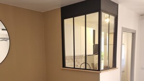 Een kamer met een bank, een spiegel en uitzicht op een keuken.