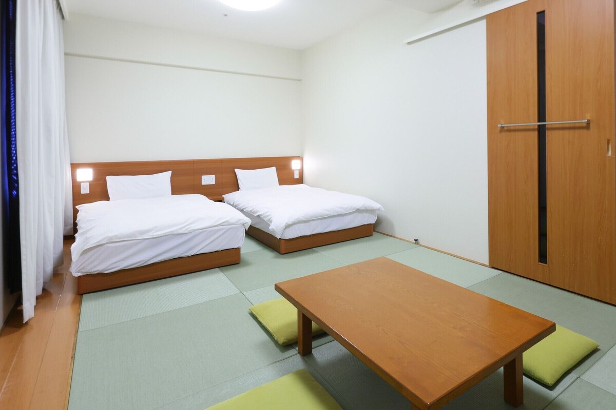 A room with two beds, a wooden table, and a wardrobe.