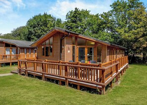 A wooden cabin with a deck, large windows, and a grassy yard. - Deluxe 3, Slps 6, parking, ensuite, decking, LV (Near Weymouth)