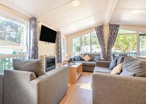 Een moderne woonkamer met een open haard, een flatscreen televisie en een zithoek.