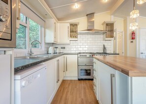 Een moderne keuken met witte kastjes, roestvrijstalen apparatuur en een houten aanrecht.