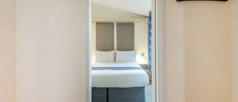 Une chambre d’hôtel avec un lit, une table de chevet et une armoire avec un miroir.