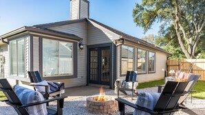 Een huis met een overdekte patio, buitenmeubels en een vuurkuil.