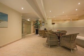 A modern indoor space with wicker furniture, a potted plant, and a tiled floor. - Südwind 13 - two bedrooms in a prime location, sauna, swimming pool and balcony (Zempin)