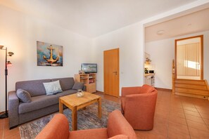 Ein Wohnzimmer mit einer Couch, Sesseln, einem Couchtisch und einem Bild von einem Anker.