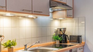 A modern kitchen with a stainless steel sink, a coffee maker, a toaster, and a built-in oven. - Villa Kaiserhof 05: Stylish vacation apartment with balcony near the beach in Zinnowitz (Zinnowitz)