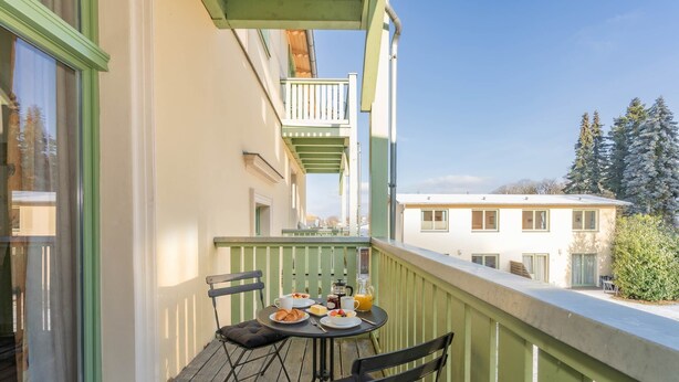 A balcony with a table set for breakfast, chairs, and a view of the city. - Villa Kaiserhof 05: Stylish vacation apartment with balcony near the beach in Zinnowitz (Zinnowitz)
