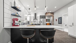 Une cuisine moderne avec un îlot central, des tabourets de bar et une arche en briques.
