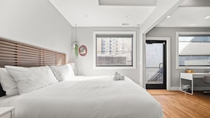 Une chambre moderne avec un grand lit, un bureau et une vue sur la ville par la fenêtre.