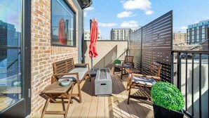 Une terrasse sur le toit, avec un mur en briques, des meubles en bois, un foyer et une vue sur le paysage urbain.