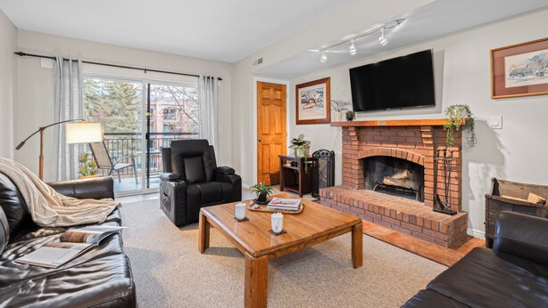 Una sala de estar con chimenea, un sofá, una mesa de centro y un televisor montado en la pared.
