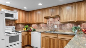 Una cocina moderna con armarios de madera, estufa blanca, lavavajillas y encimera de granito.