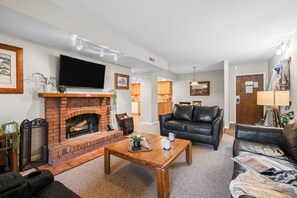 A living room with a fireplace, leather sofas, a coffee table, and a TV mounted on the wall. - Cozy Old Town Condo + Fireplace + Balcony + Near Skiing, Dining, and Trails (Park City)