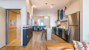 Una cocina moderna con una isla central, electrodomésticos de acero inoxidable y un comedor con sillas y una mesa.