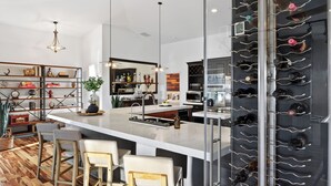A modern kitchen with a central island, bar stools, a wine rack, and a variety of kitchen appliances. - Waterfront, Infinity Pool, Dock, Outdoor Bar, Beach Access | Riverside Veranda (Fort Lauderdale)