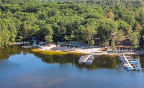A lakeside resort with boats docked, a sandy beach, and a forested area. - Lake Harmony Home • Loft + Game Room • Near Lake + Ski | Mountain Laurel Lodge (Lake Harmony)
