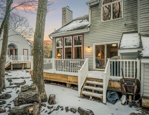Een tweelaags huis met een houten terras, een veranda en een garage.